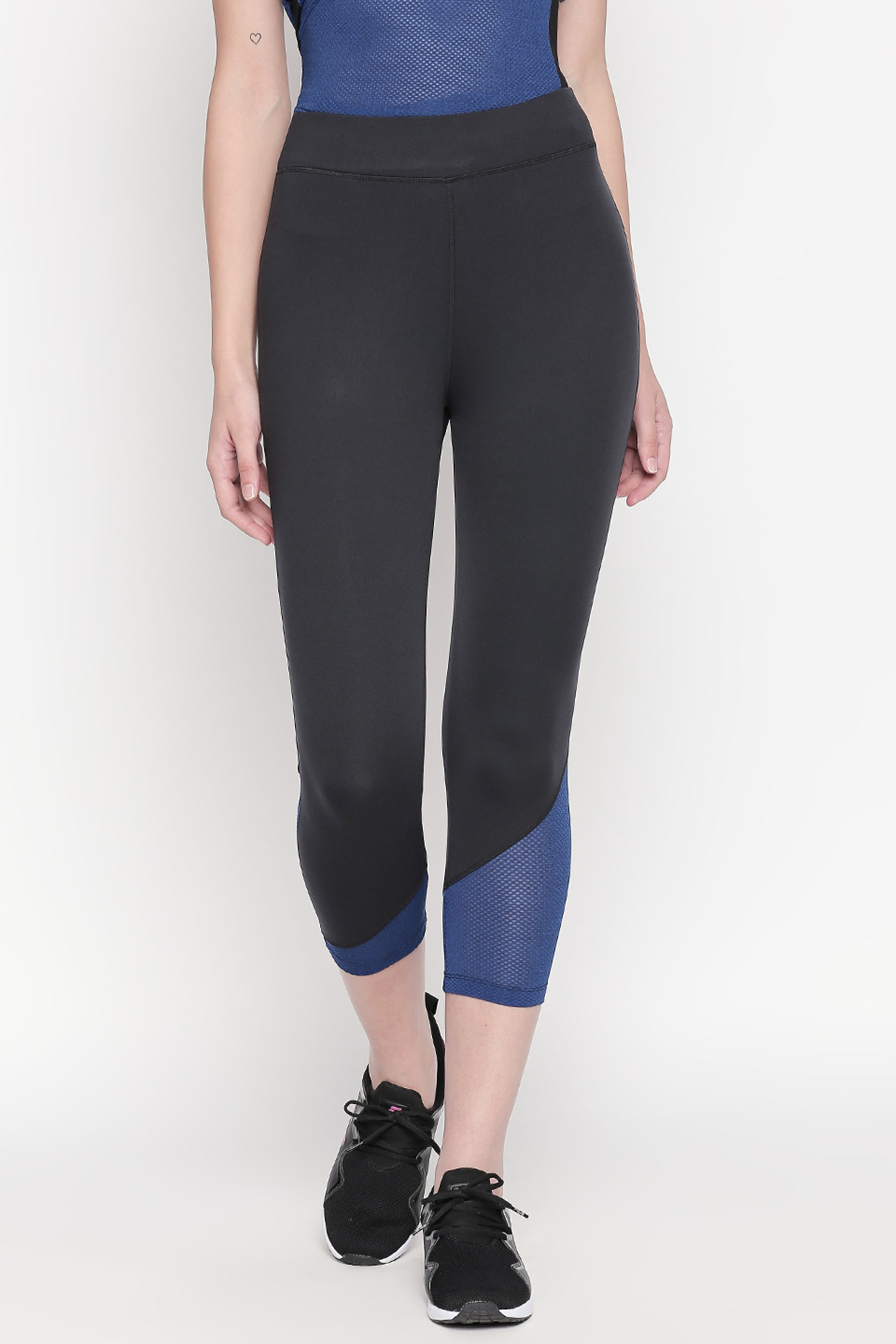 A woman is wearing the Sportswear Dark Blue Tracksuit featuring solid knitted leggings with blue detailing, black sneakers, and a netted blue top.