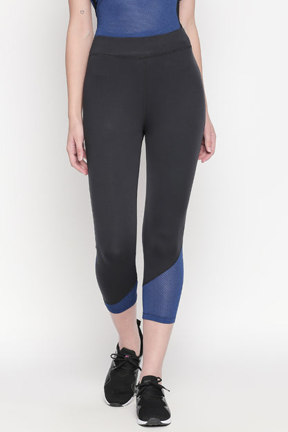 A woman is wearing the Sportswear Dark Blue Tracksuit featuring solid knitted leggings with blue detailing, black sneakers, and a netted blue top.