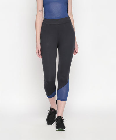 Woman stands against a white background wearing Black High Waisted Leggings 74 with blue accents and black sneakers.