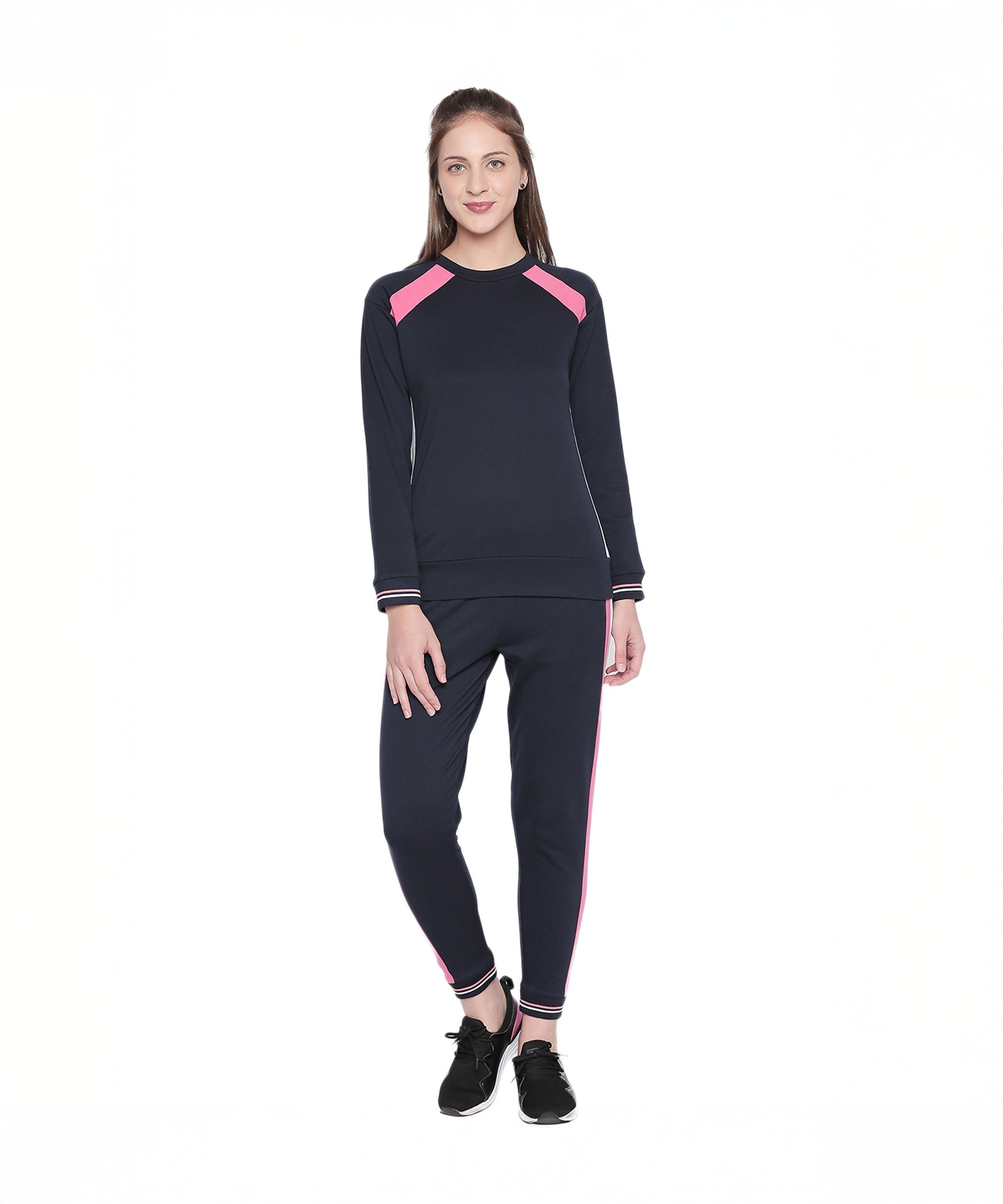 A woman stands smiling in a Sportswear Navy Blue Tracksuit featuring pink stripes, ideal for home workouts or casual outings, set against a white background.