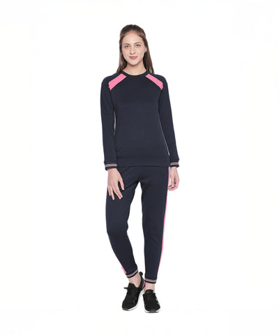 A woman stands smiling in a Sportswear Navy Blue Tracksuit featuring pink stripes, ideal for home workouts or casual outings, set against a white background.