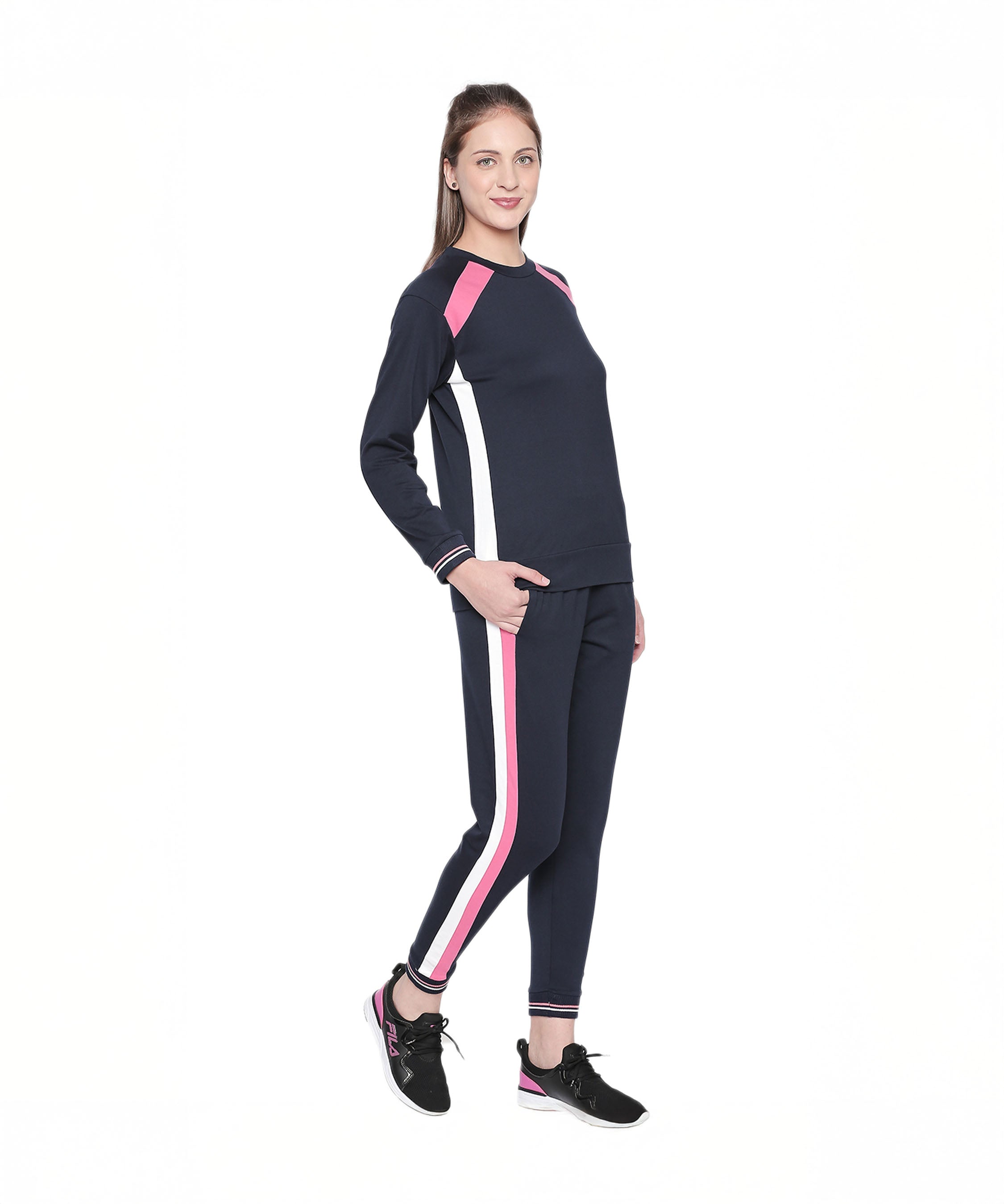 Model wearing the Sportswear Navy Blue Tracksuit featuring pink and white stripes, ideal for home workouts or casual athleisure. Paired with black sneakers, she stands smiling against a white background.
