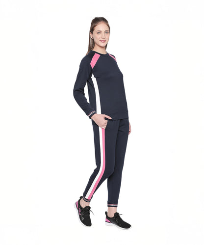 Model wearing the Sportswear Navy Blue Tracksuit featuring pink and white stripes, ideal for home workouts or casual athleisure. Paired with black sneakers, she stands smiling against a white background.