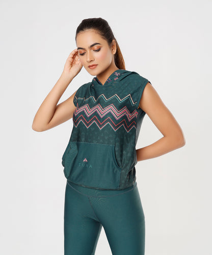 Woman wearing the Tuna Active Teal Hooded Top with an ombre zigzag pattern, posing with one hand near her face against a white background.