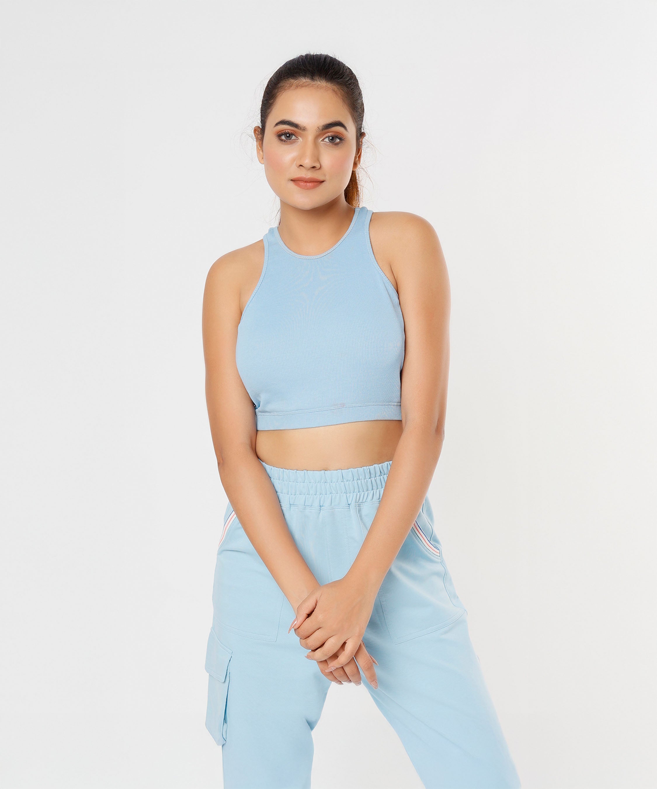 Woman wearing the Blossom Blue Set with a sleeveless crop top and cargo track pants, posing against a plain white background.
