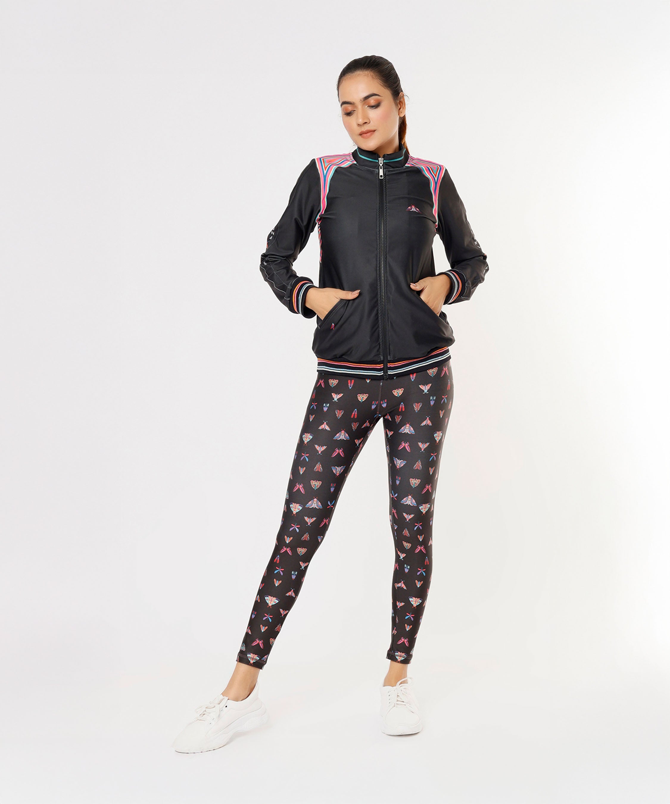 Woman wearing the Tuna Active Black Bomber Jacket and patterned leggings, standing with hands in pockets against a white background.