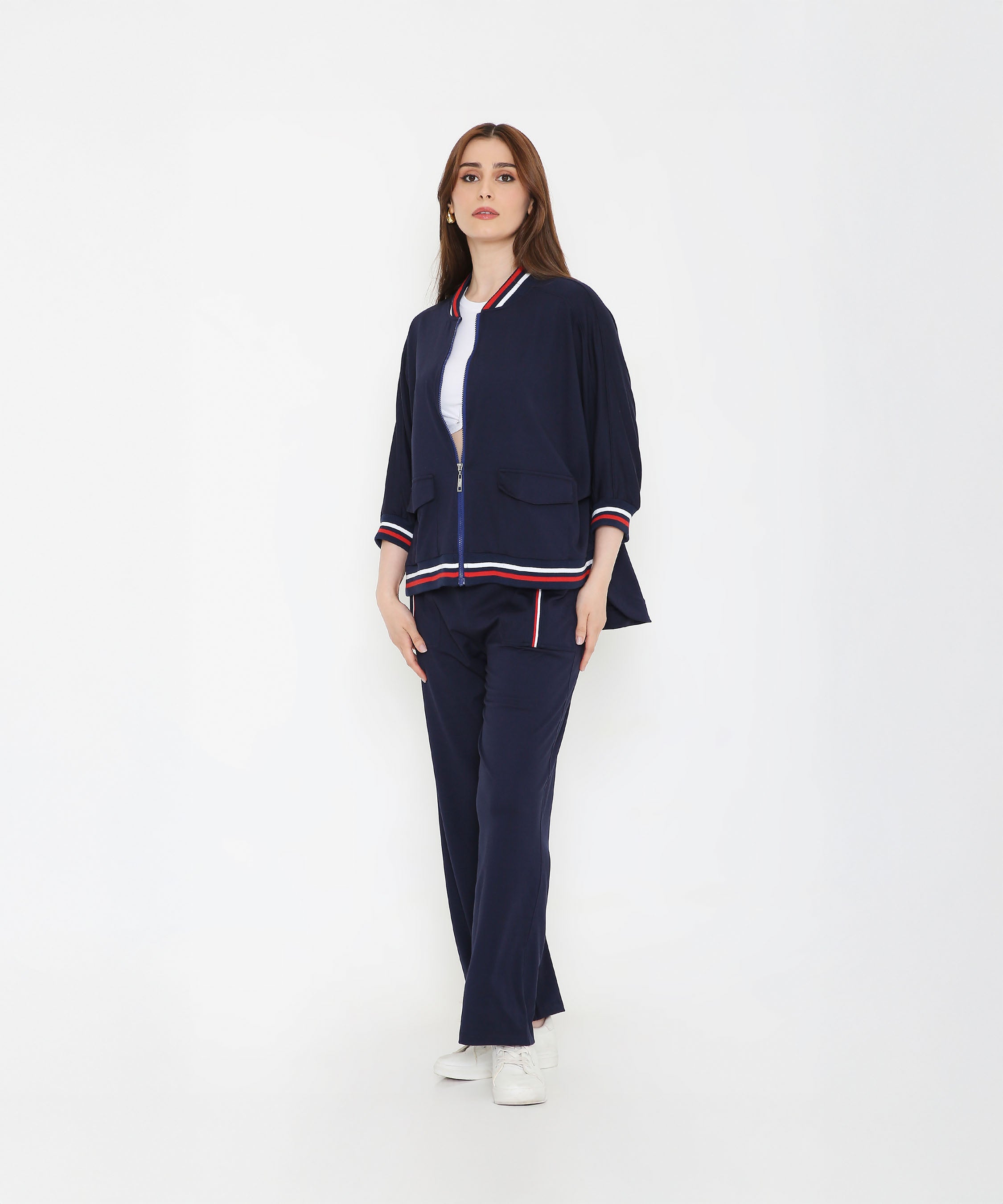 Woman wearing the Navy Blue Zipped Long Jacket with Tracks, featuring red and white stripes—a stylish and sporty women’s activewear set against a plain white background.