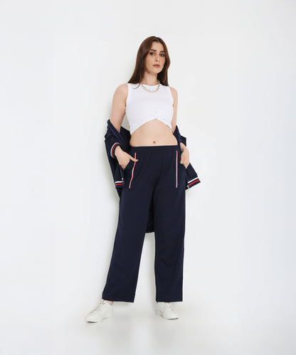 Woman in a white tank top and Navy Blue Zipped Long Jacket with Tracks, hands in pockets, white sneakers—a chic and effortless look in women’s activewear.