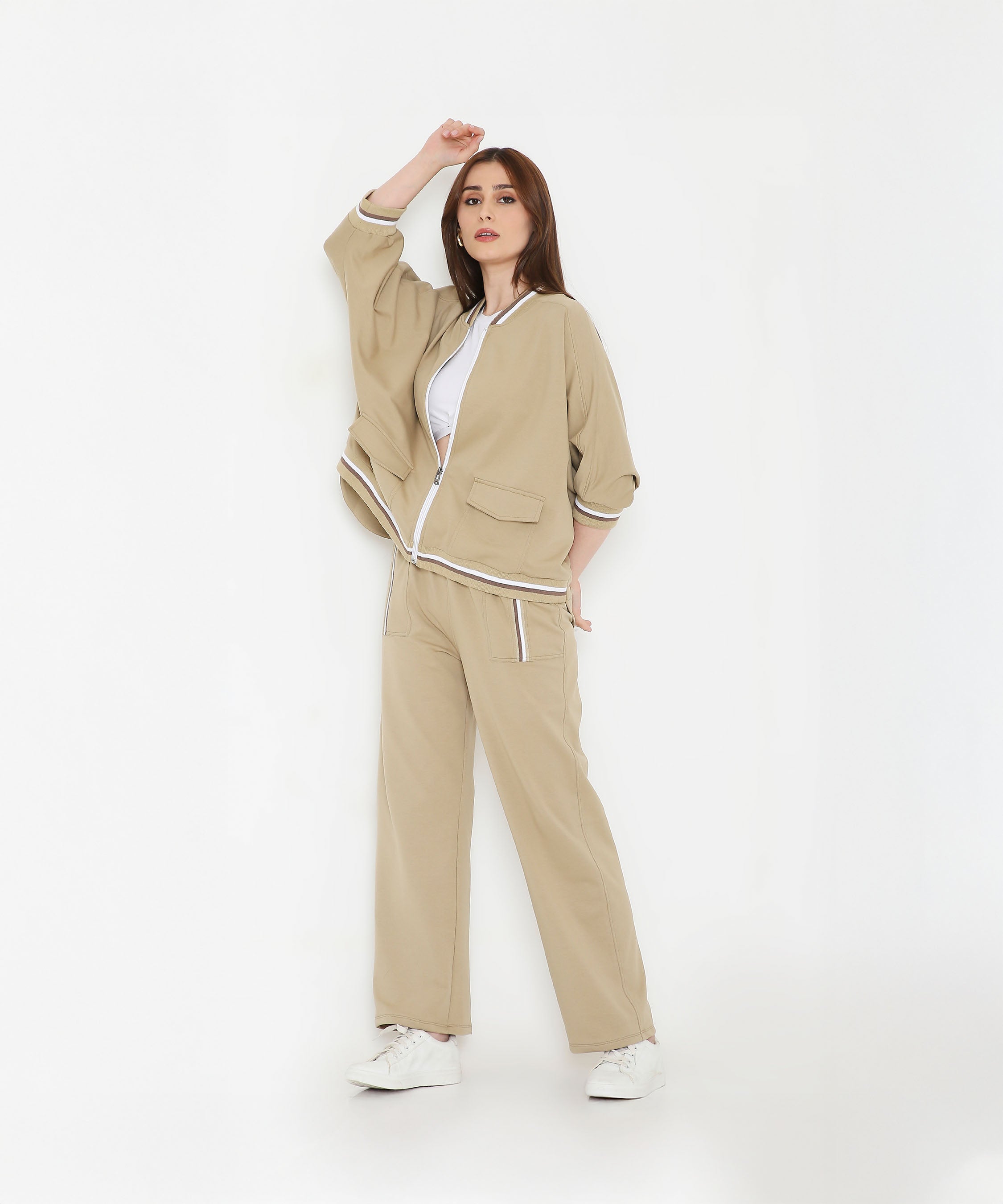 Woman wearing the Beige Zipped Long Jacket with Tracks, paired with a white top and sneakers—ideal women’s activewear for a stylish and comfortable look.