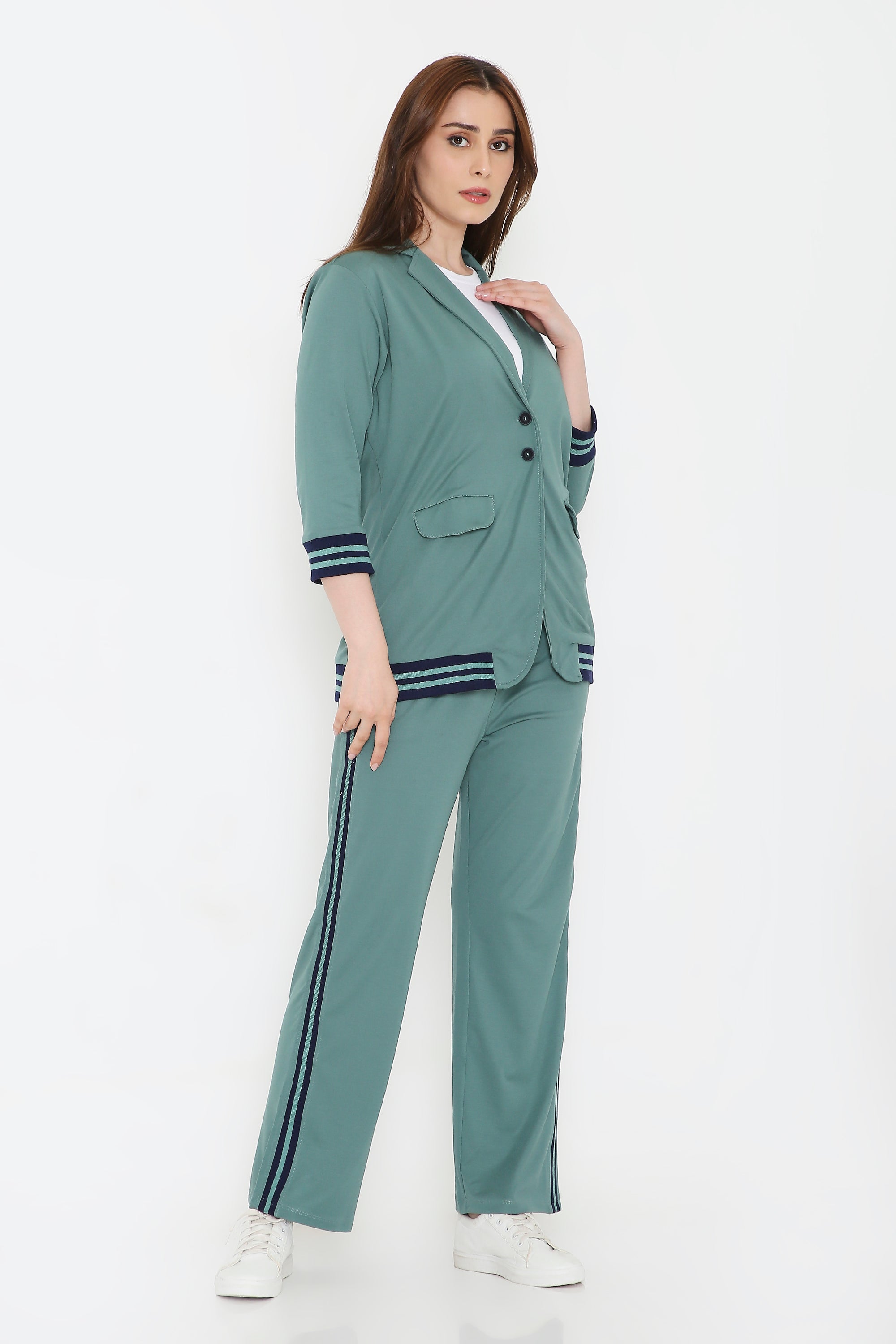 A woman confidently poses in the Sage Green Athleisure Blazer Jacket and Track Set, paired with white sneakers against a white background.