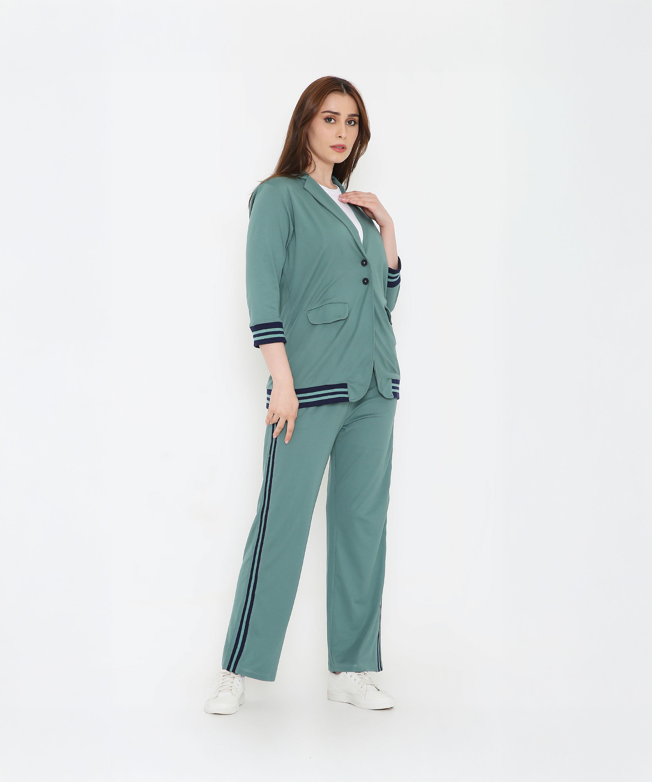 A woman confidently poses in the Sage Green Athleisure Blazer Jacket and Track Set, paired with white sneakers against a white background.