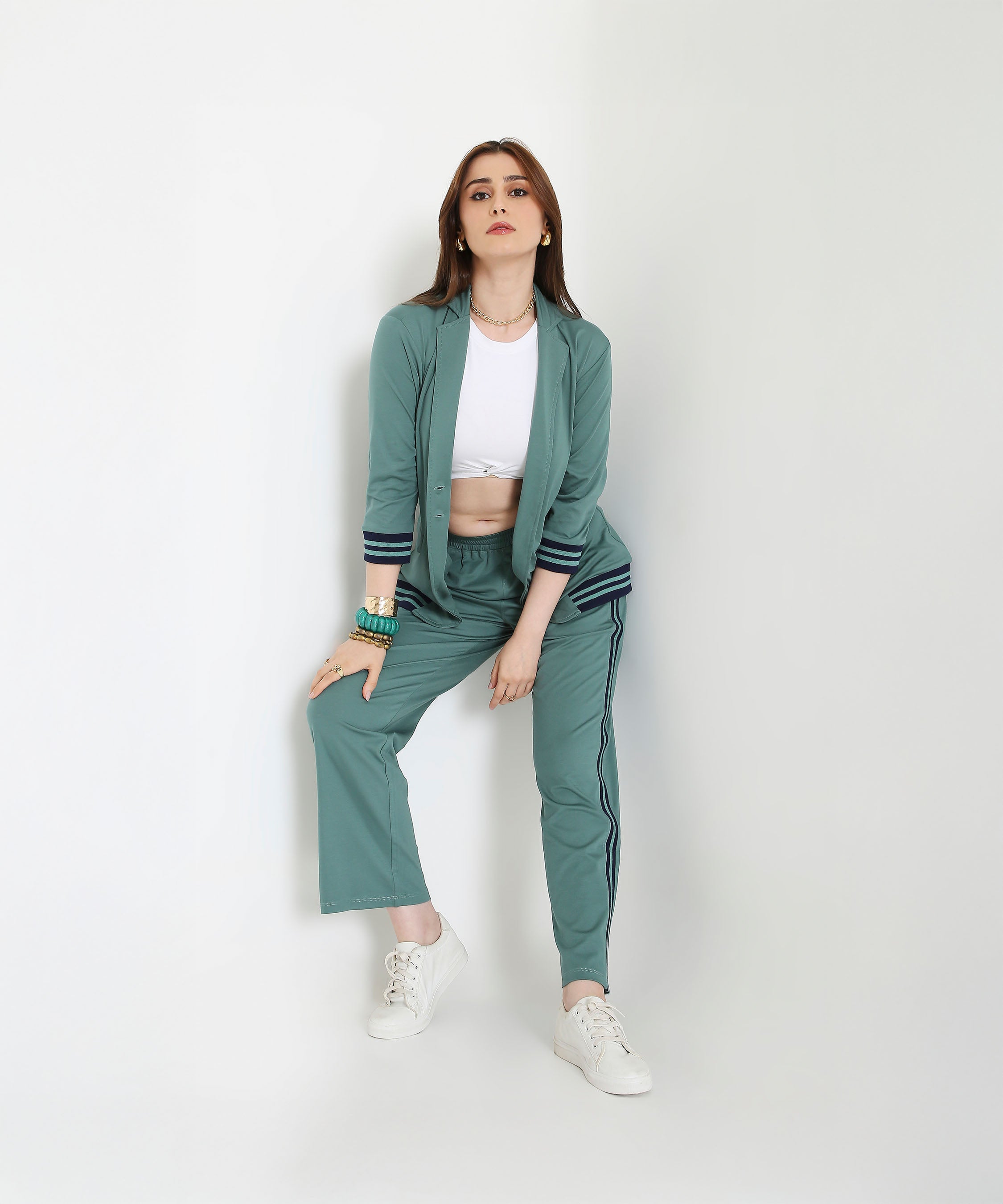 Woman wearing the Sage Green Athleisure Blazer Jacket and Track Set with a white crop top and sneakers, posing against a plain white background.