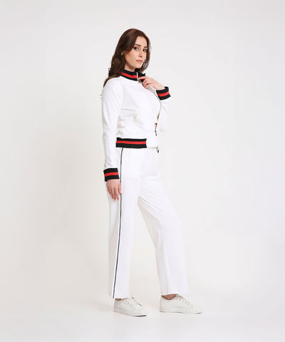 A woman models the Two Piece Bold Contrast White Tracksuit, featuring black and red trim on soft cotton-blend fabric, styled with white sneakers for a modern sporty-chic look.