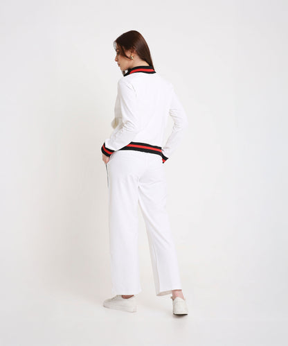 Woman sporting the Two Piece Bold Contrast White Tracksuit, featuring black and red trim on cotton-blend fabric, hands in pockets and facing away for a chic, modern look.