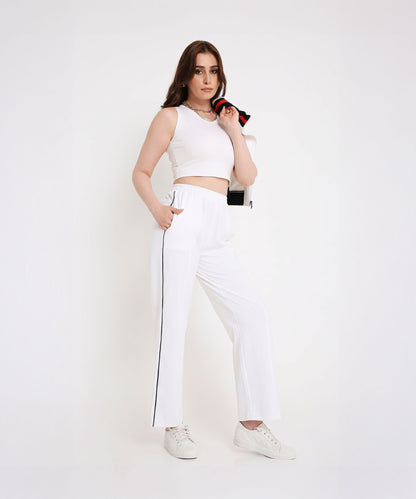 Confident woman in a sporty-chic style wears the Two Piece Bold Contrast White Tracksuit, featuring side stripes and a cotton-blend fabric, with the jacket draped over one shoulder.