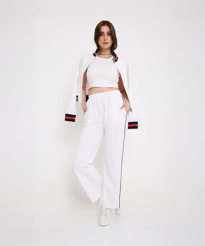 Woman in a sporty-chic look, wearing the Two Piece Bold Contrast White Tracksuit—white crop top and matching jacket with black striped pants—stands against a white background.