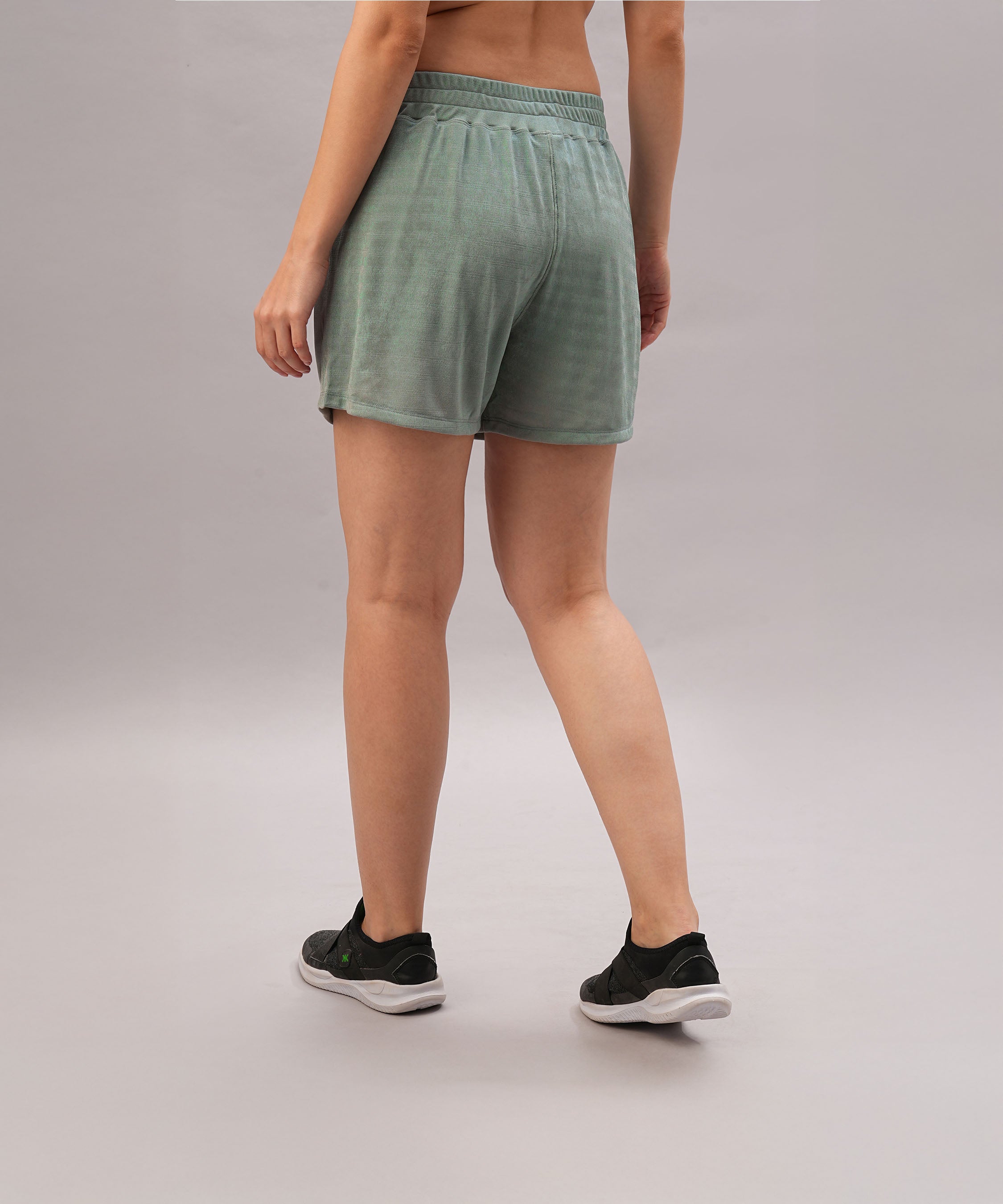 Model wearing Tie up Shorts in green with an elastic waistband and black sneakers, standing against a plain light background, shown from the back.