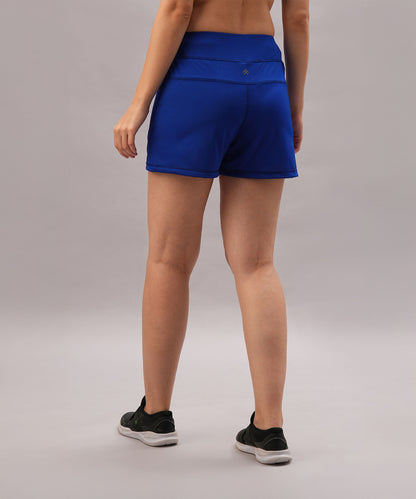 Person wearing Blue Premium Stretch Shorts With Lining and black shoes stands on a gray background, facing away from the camera.