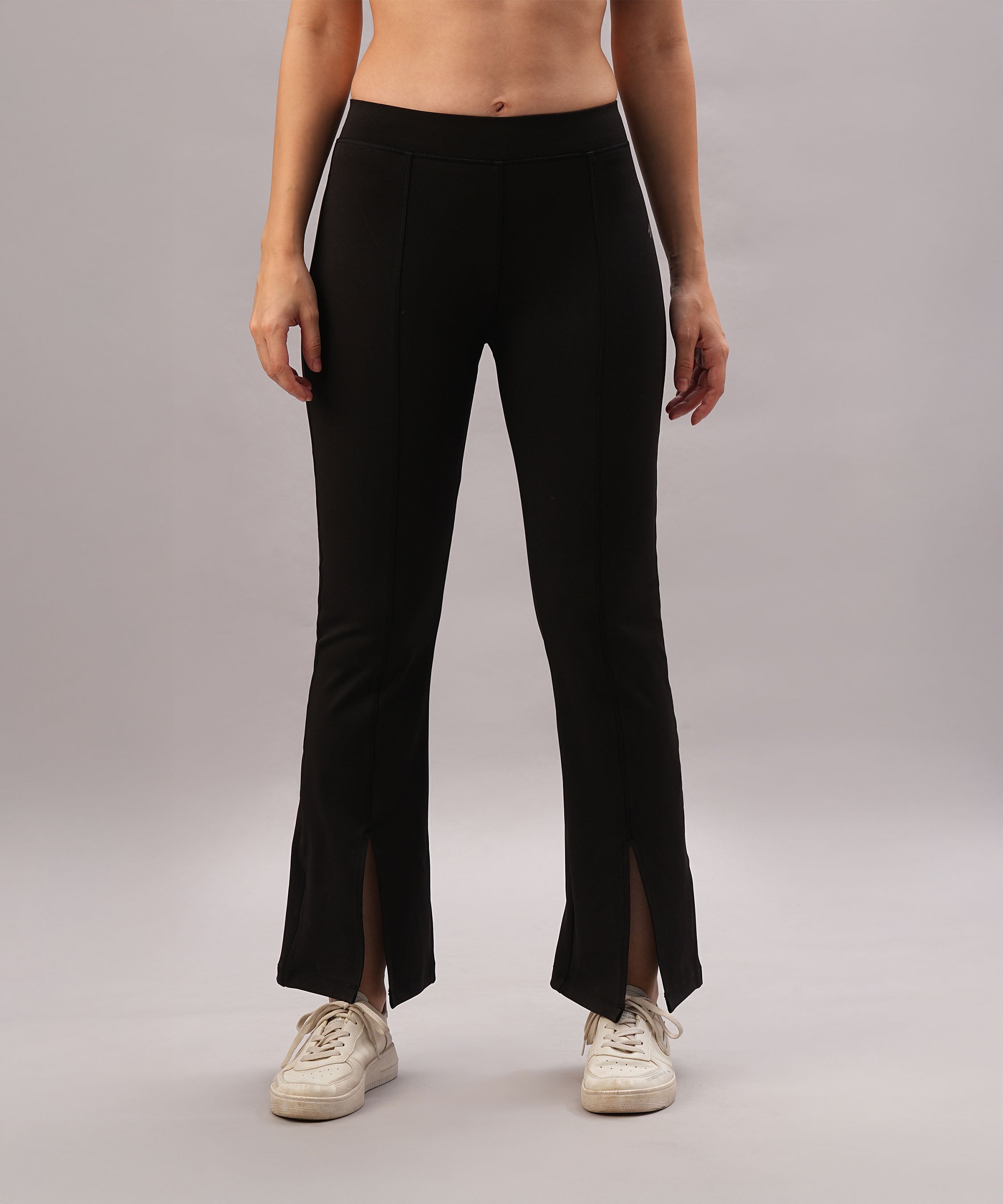 Someone wearing Black Slit Leggings and white sneakers stands against a plain background.
