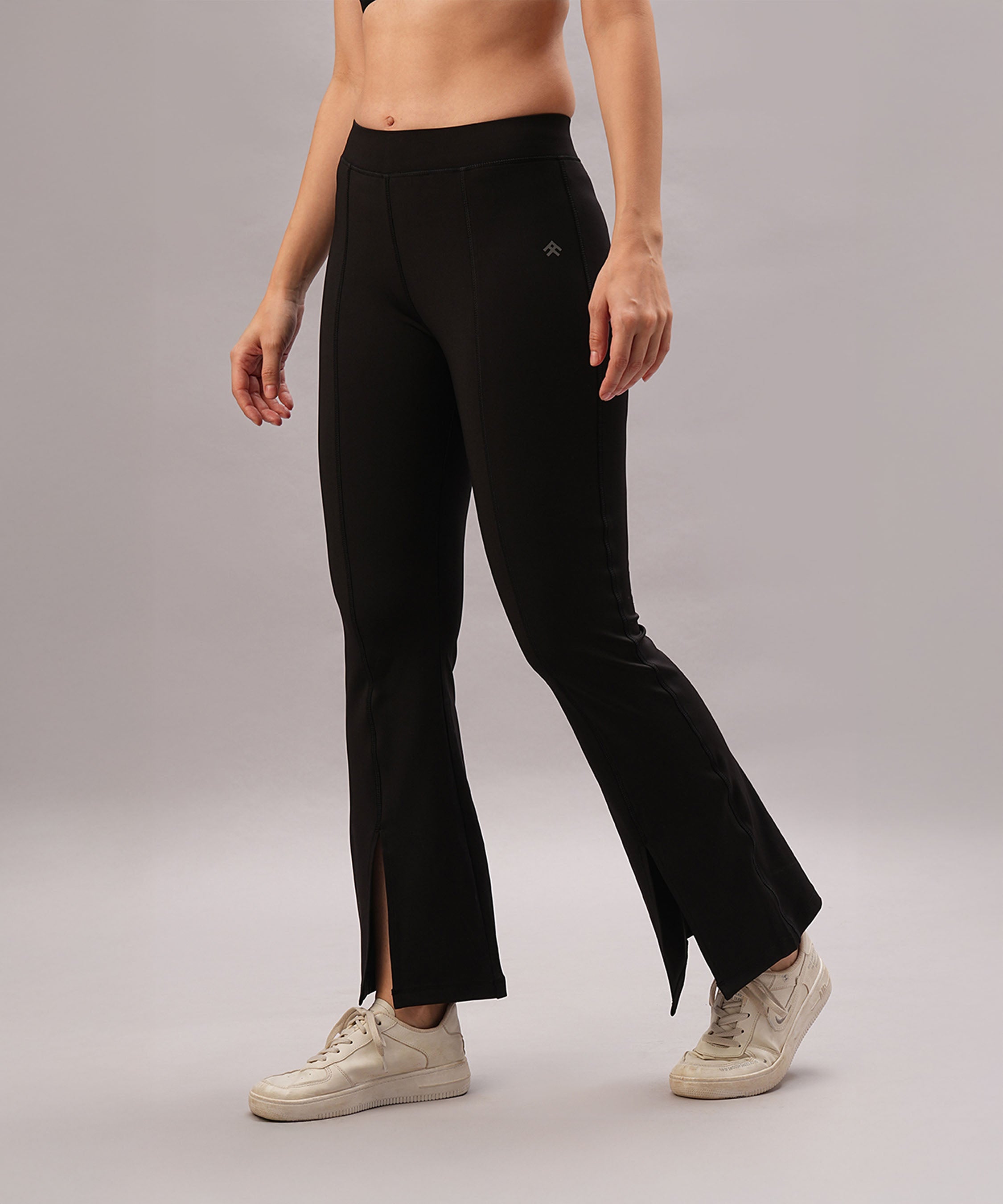 Model wears Black Slit Leggings featuring front slits, paired with white sneakers, standing against a plain background.