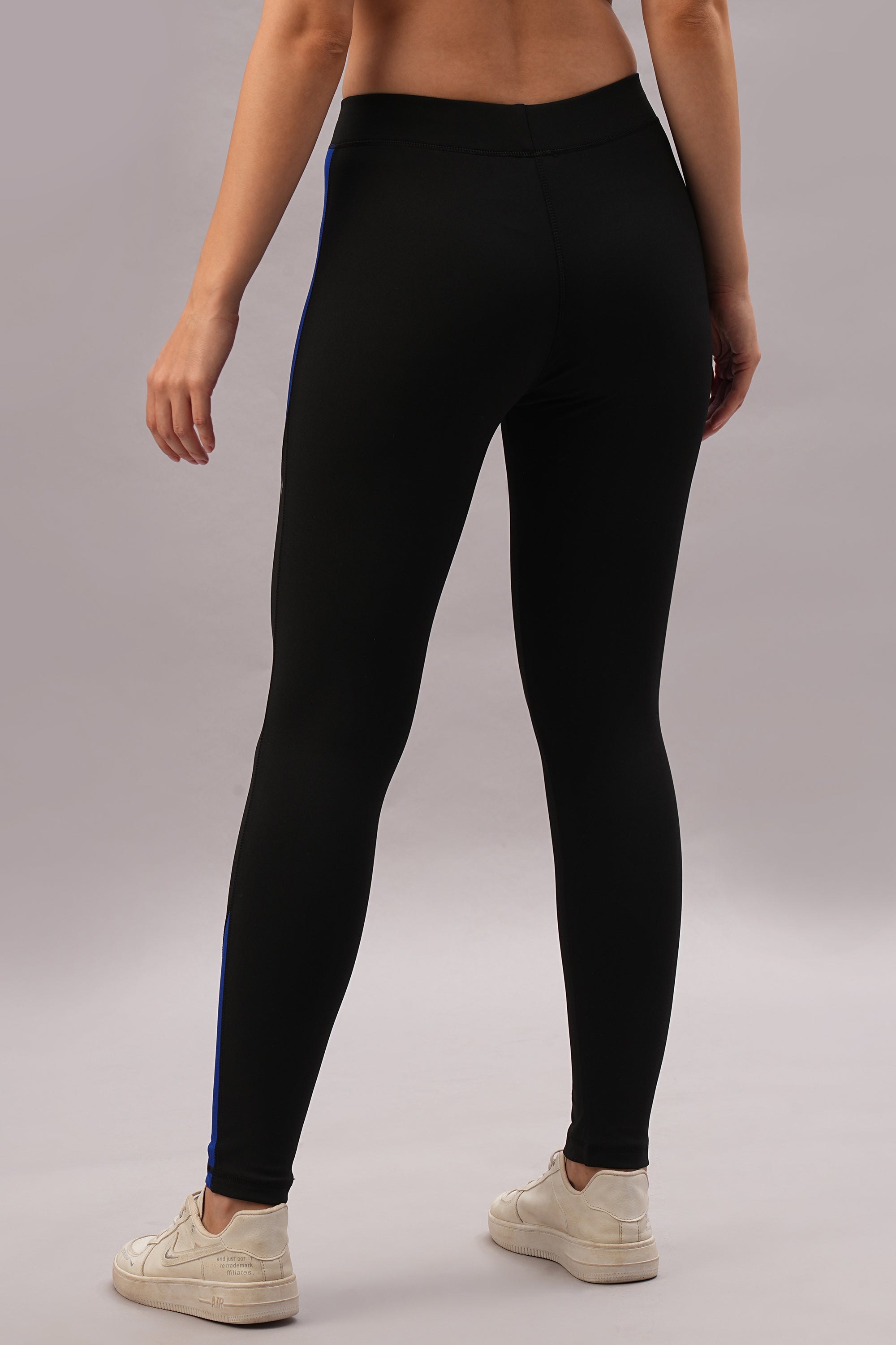 Model wearing Black and Blue Pants with a tailored fit, paired with white sneakers, shown from the back against a plain background.