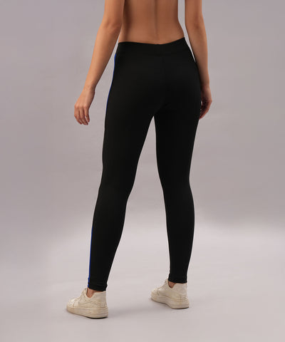 A woman showcases Black and Blue Pants with a high-performance fit, made from four-way stretch fabric for ultimate comfort, against a plain, light-colored background.
