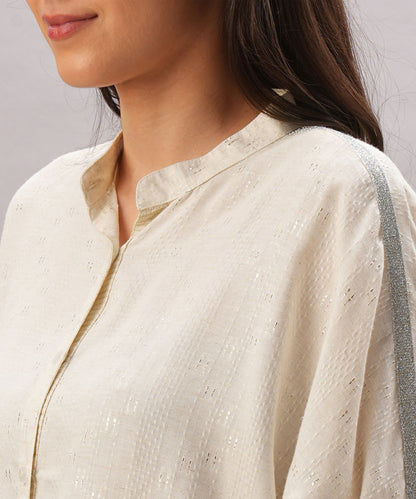 A woman wears the Beige Linen Set, featuring a cream-colored textured kurta with a metallic silver shoulder stripe, crafted from breathable linen for a relaxed fit.