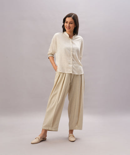 A woman smiles with hands in pockets, wearing the Beige Linen Set—a relaxed fit ensemble featuring loose, breathable linen pants and a matching button-up shirt.