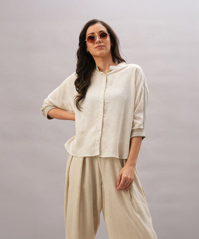 A woman in a relaxed fit Beige Linen Set and sunglasses poses confidently against a light gray background, highlighting the effortless elegance and breathability of the Beige Linen Set.