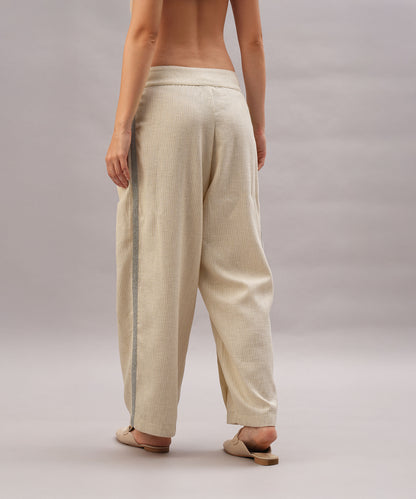 A person is seen from the back in a Beige Linen Set and sandals against a plain backdrop, emphasizing the set’s relaxed fit and breathable linen fabric.