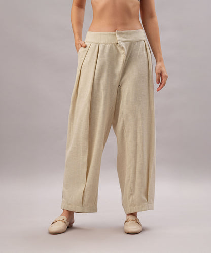 Person wearing the Beige Linen Set, featuring relaxed fit and pleated trousers, paired with beige shoes and hands in pockets against a plain background.