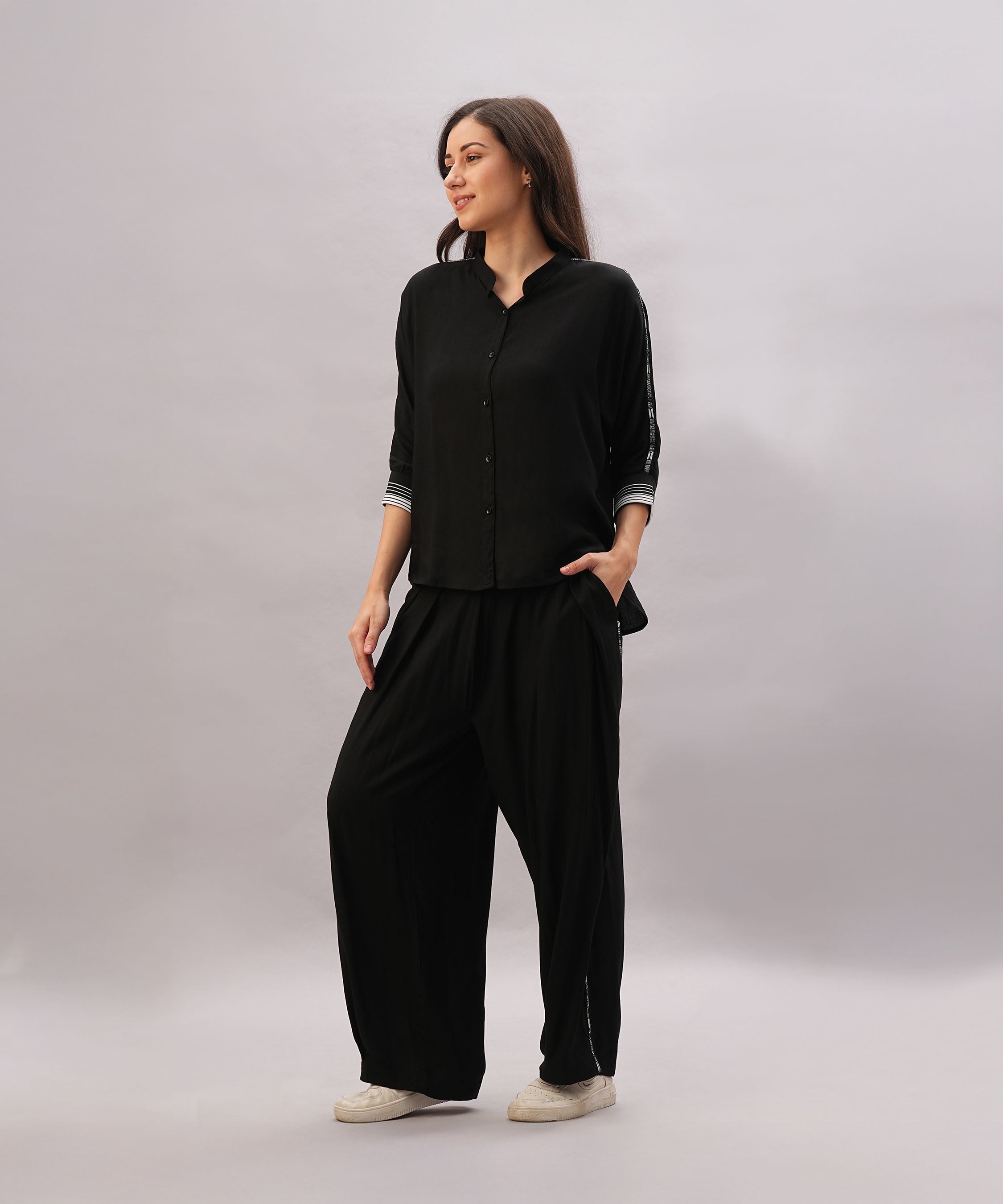 A woman models the Black Rayon Co-Ord Set, featuring a loose button-up shirt and relaxed-fit pants, against a light gray background.