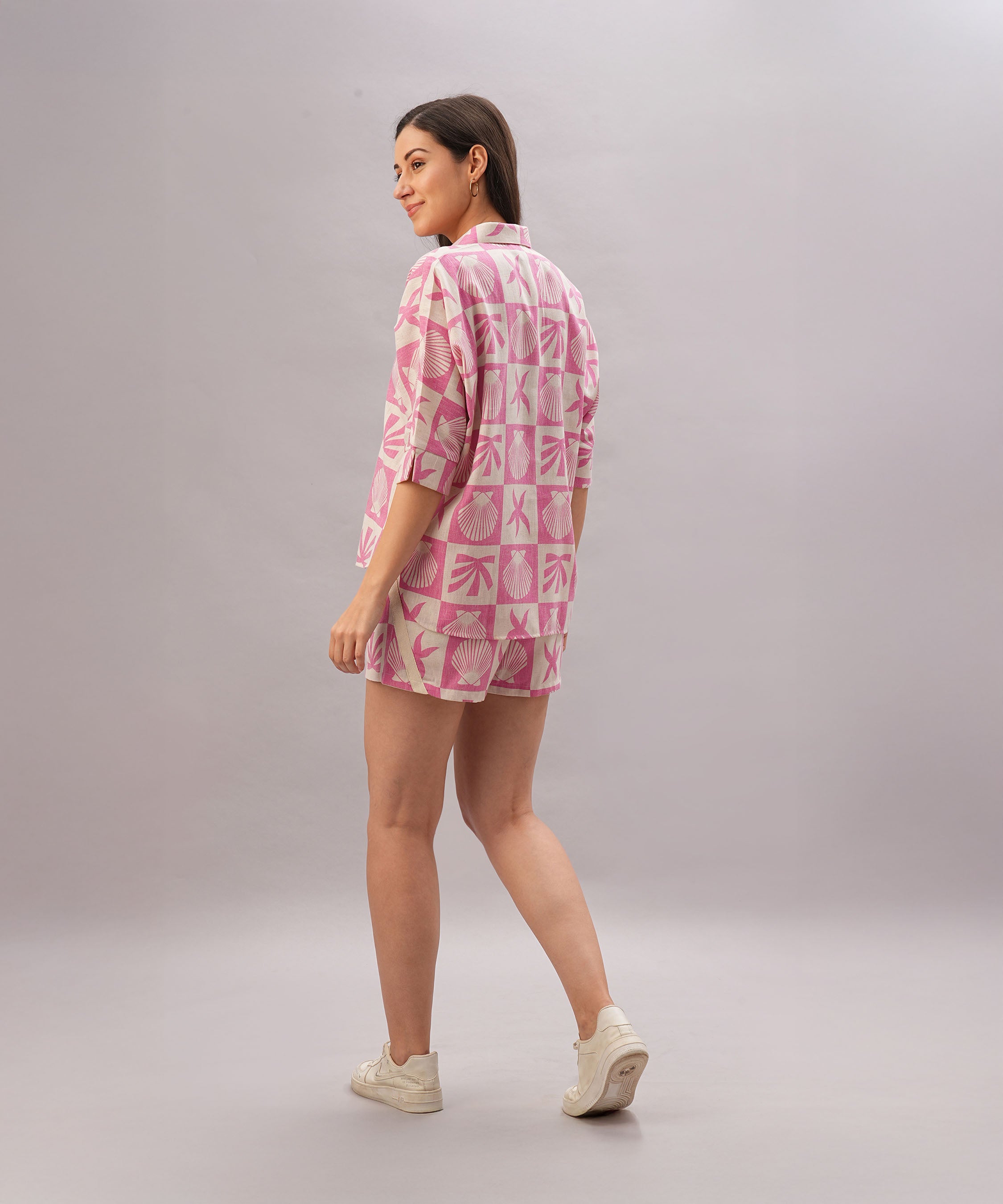 A woman models the Pink Co-Ord Set, featuring stylish matching bottoms and a trendy top, as she stands looking over her shoulder.