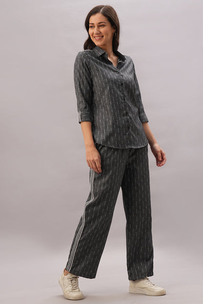 Woman wearing the Grey Stripes Sleeves Set—a stylish top with matching pants—paired with white sneakers, standing and smiling against a gray background. Made from comfortable fabric for effortless style.