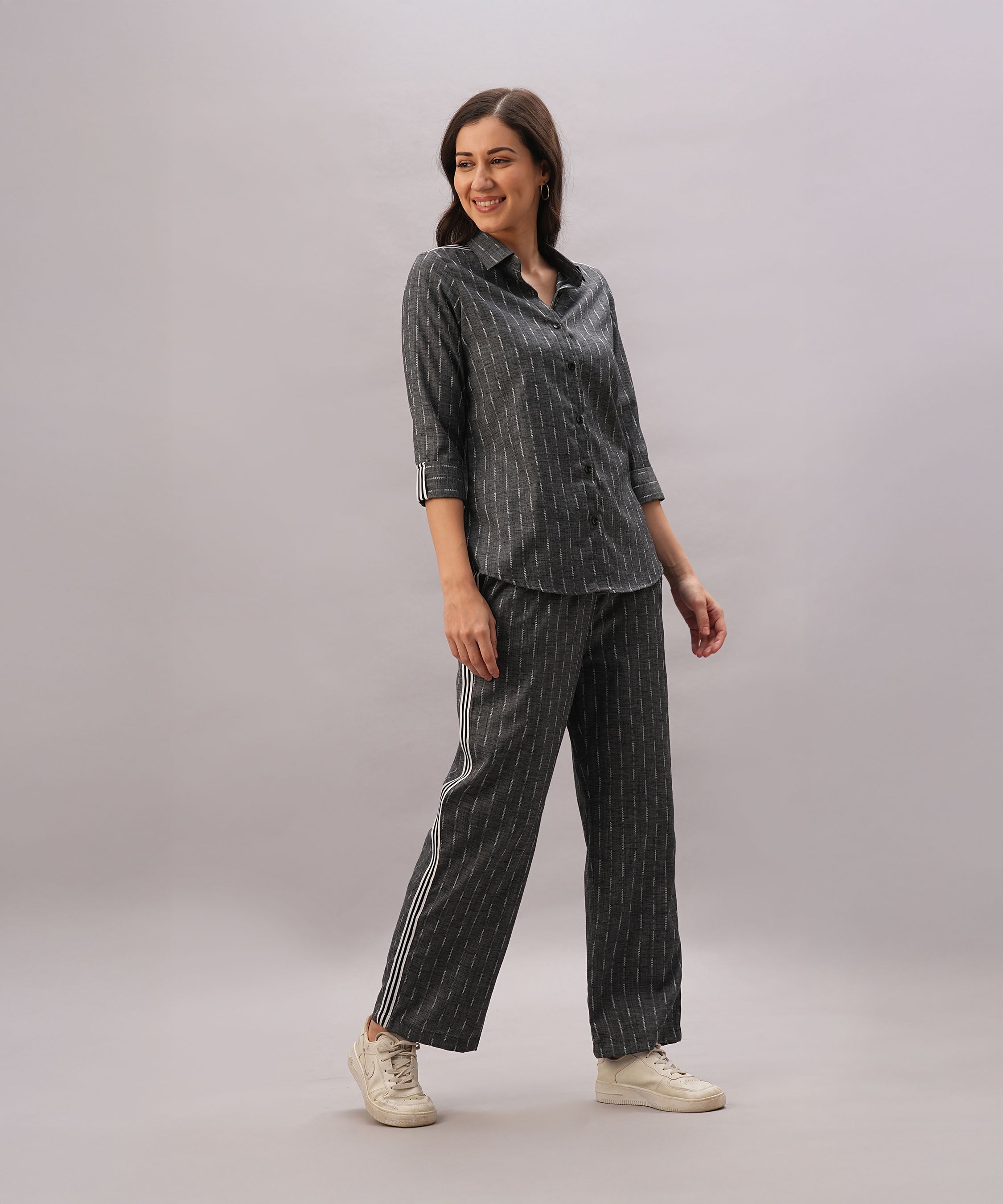 A woman smiles in the Grey Stripes Sleeves Set—coordinated dark striped shirt and matching pants in comfortable fabric—paired with white shoes, standing against a plain background.