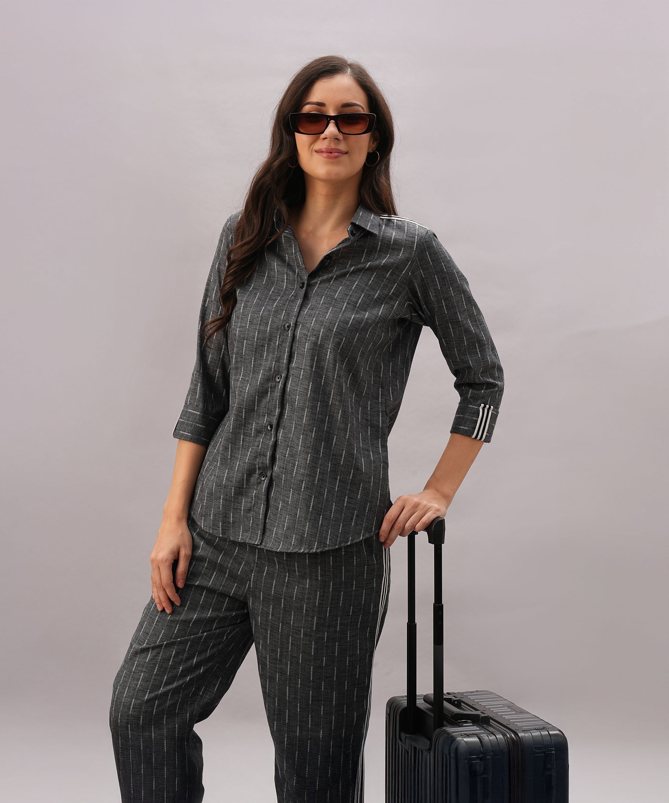 A woman wearing the Grey Stripes Sleeves Set and sunglasses stands with her hand on a suitcase, highlighting a coordinated style against a plain background.