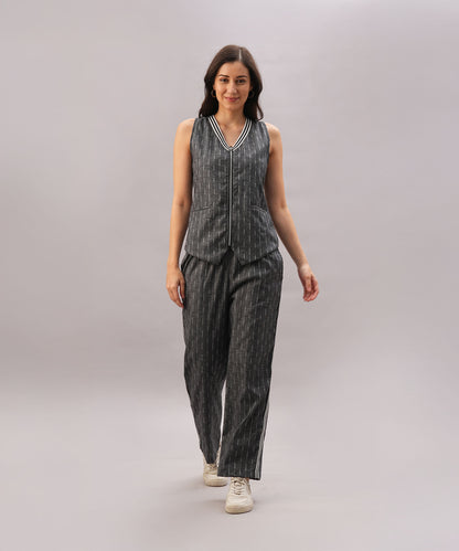 A woman models the Grey Stripes Sleeveless Set with white sneakers, walking against a plain light gray background.