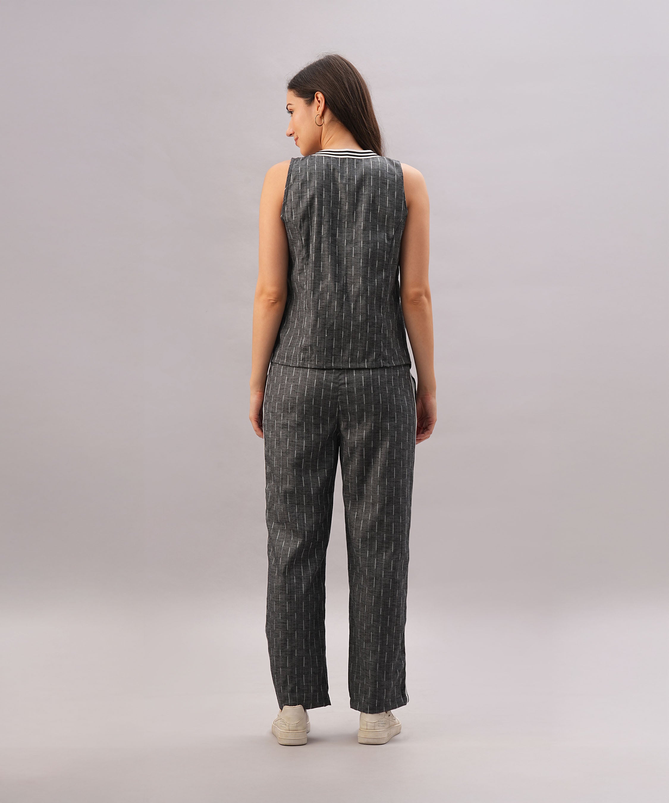 A woman stands with her back to the camera, highlighting the chic Grey Stripes Sleeveless Set against a plain background.