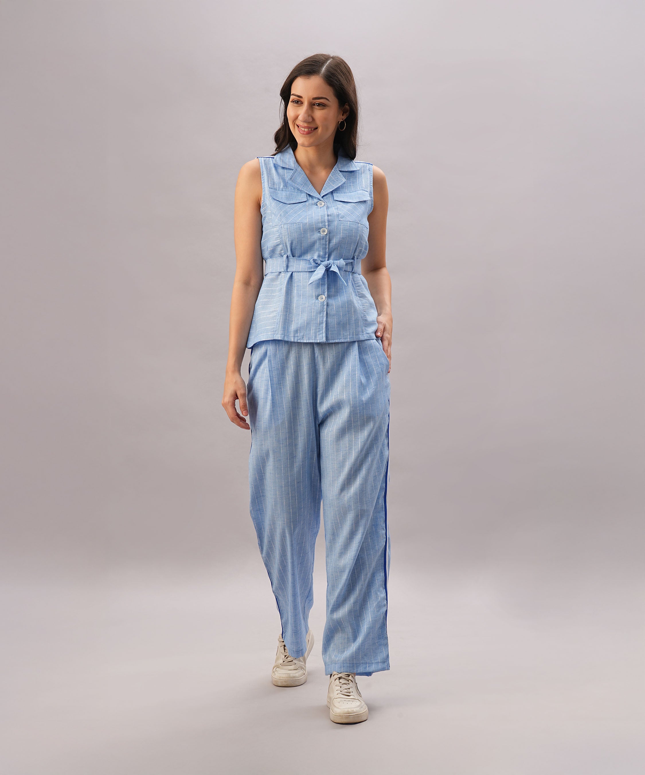 A woman smiles as she walks, wearing the Light Blue Stripes Co-Ord Set with a sleeveless top and matching wide-leg pants.