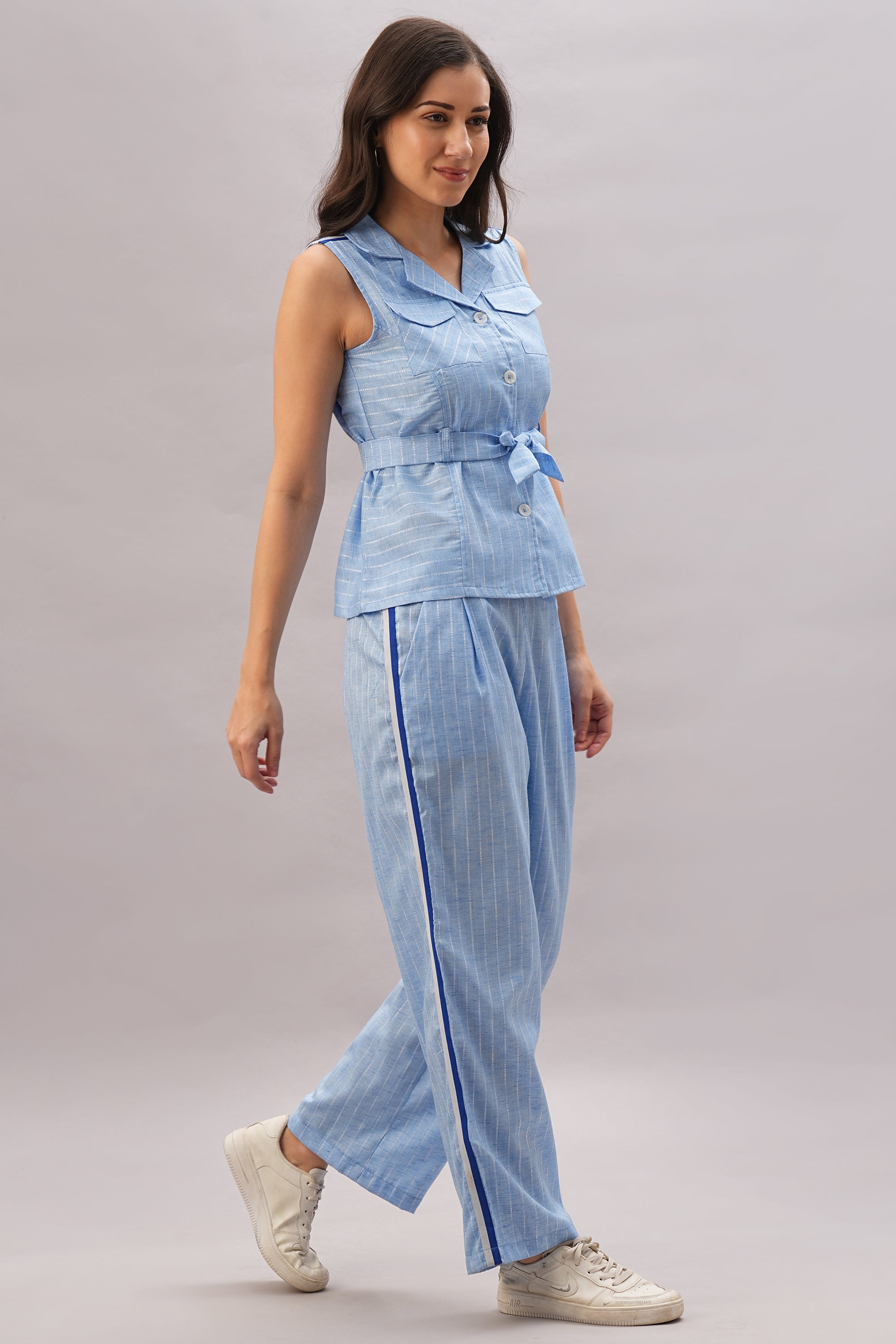 A woman walks and smiles in a Light Blue Stripes Co-Ord Set paired with white sneakers.