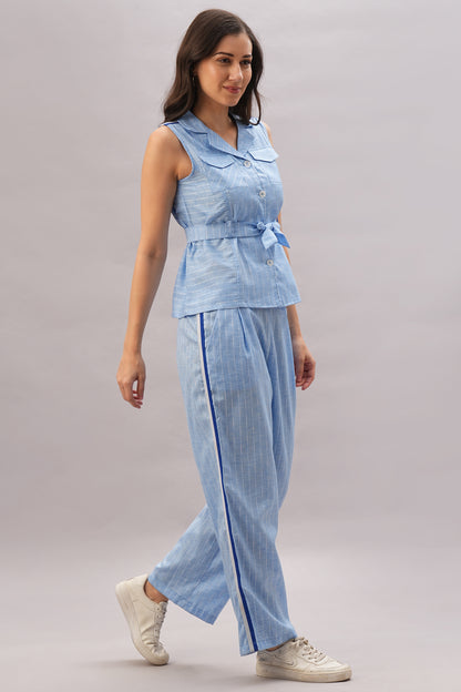 A woman walks and smiles in a Light Blue Stripes Co-Ord Set paired with white sneakers.