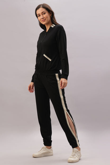 Woman wearing a Black Co-Ord Set with white stripes and a chic top, paired with white sneakers, standing and smiling against a light background.