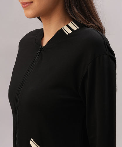 A woman wearing the Black Co-Ord Set featuring a black cotton lycra zip-up jacket with cream striped collar and pocket details, facing left—a chic option for coordinated style.