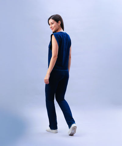 Smiling woman wears the Blue Denim Wash Capsleeves Tops and Bootcut Leggings Set, featuring high-waisted bootcut leggings, and looks over her shoulder while standing against a light background.