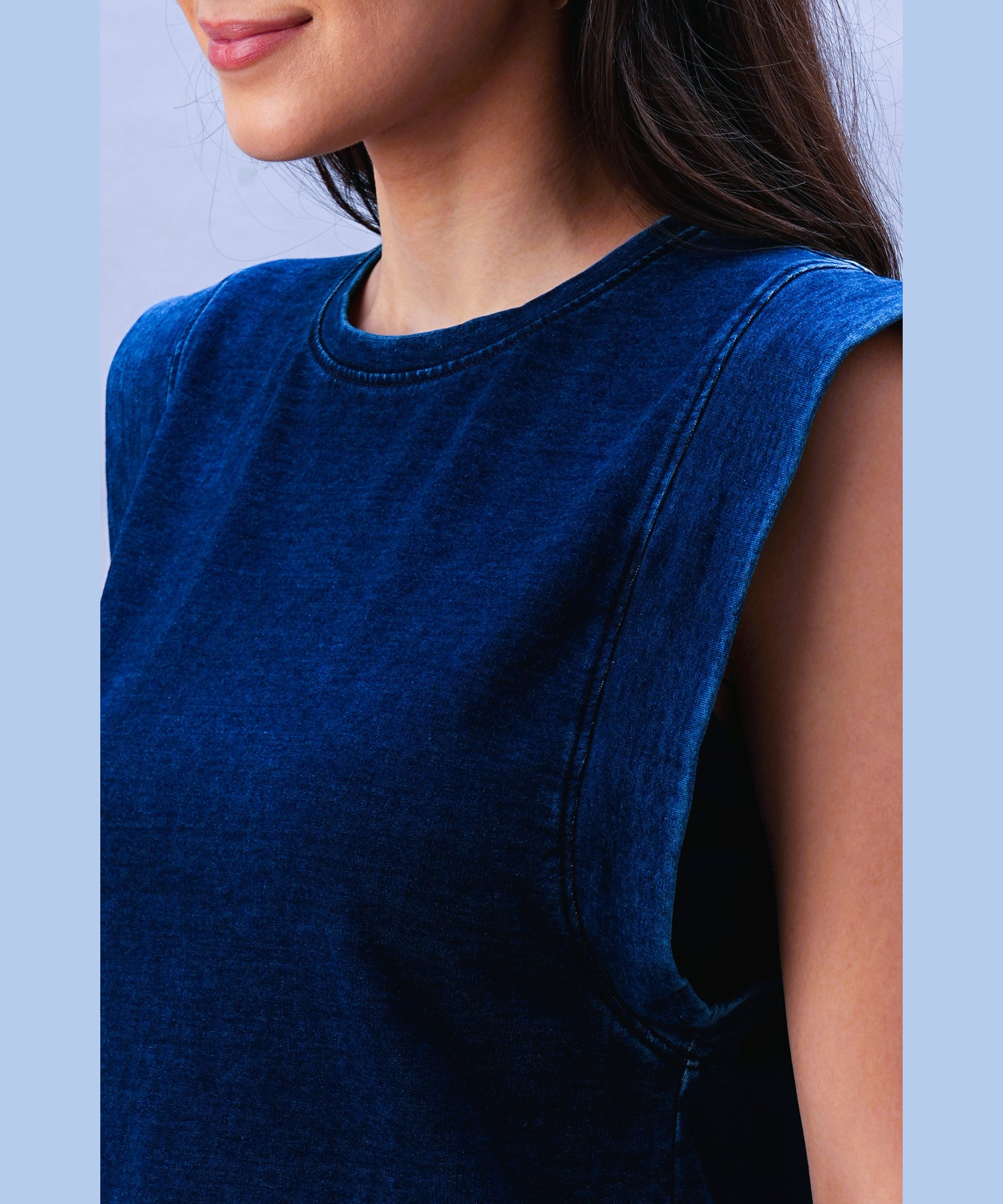 A woman models the Blue Denim Wash Capsleeves Top, showcasing its casual sleeveless style from the shoulders to just above her lips.