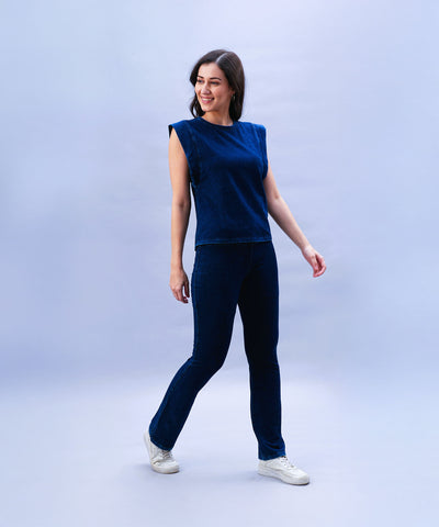Smiling woman in a blue sleeveless top and Blue Denim Wash Bootcut Leggings, posing against a light blue background.