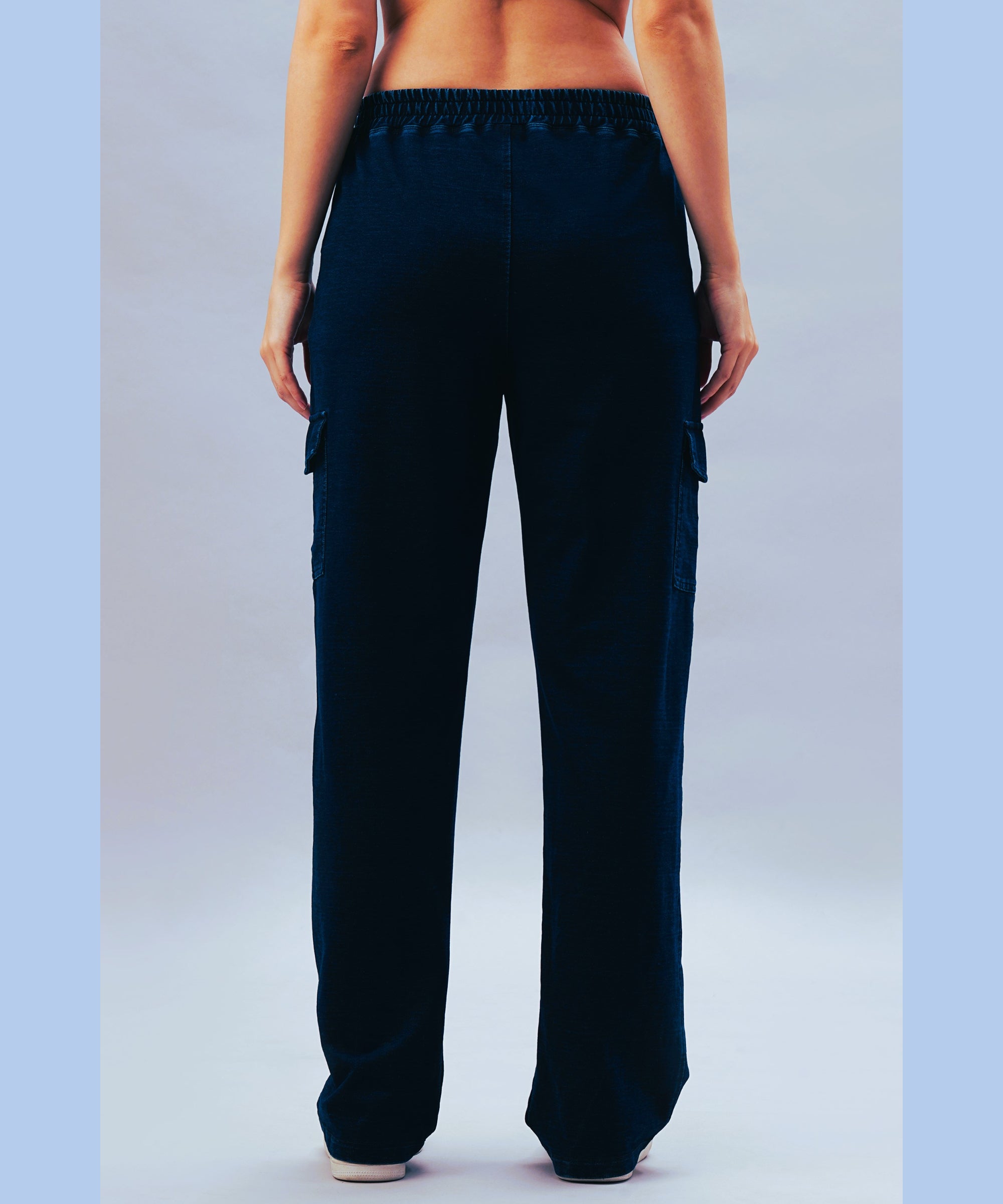 A person is shown from the back wearing the Blue Denim Wash Cargo Trackpant and white shoes against a light background.