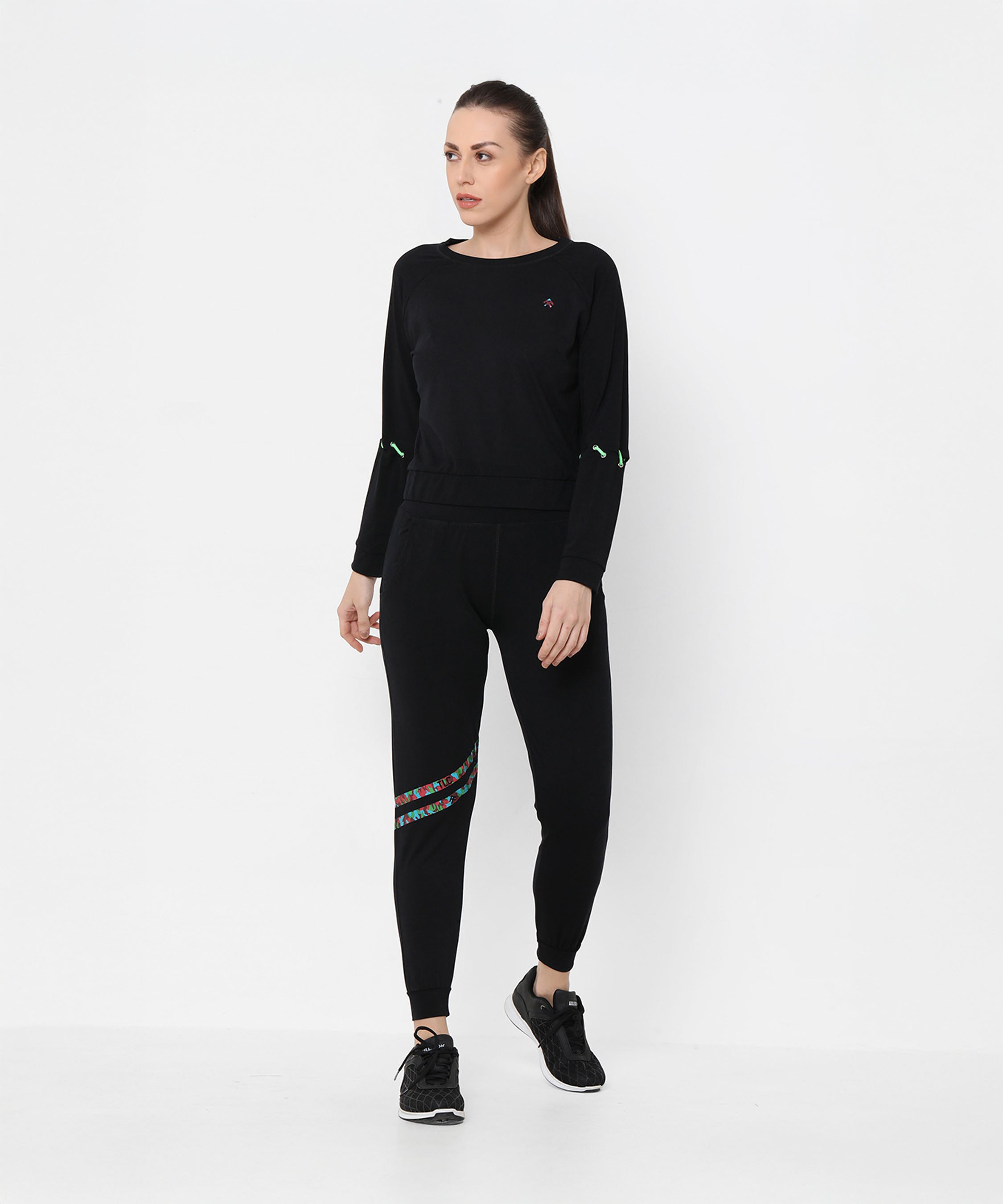 A woman wearing the Black Sweatshirt With Joggers featuring iridescent camo tape and sneakers poses against a plain white background.