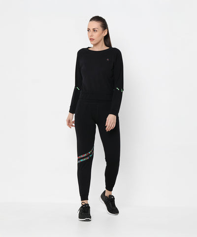 A woman wearing the Black Sweatshirt With Joggers featuring iridescent camo tape and sneakers poses against a plain white background.