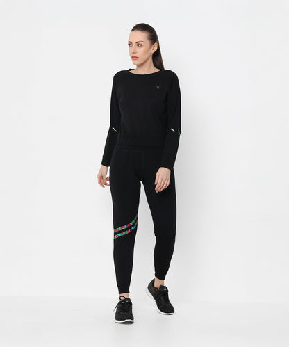 A woman wearing the Black Sweatshirt With Joggers featuring iridescent camo tape and sneakers poses against a plain white background.